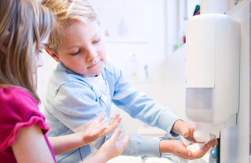 Two kids taking soap from a dispenser (photo)