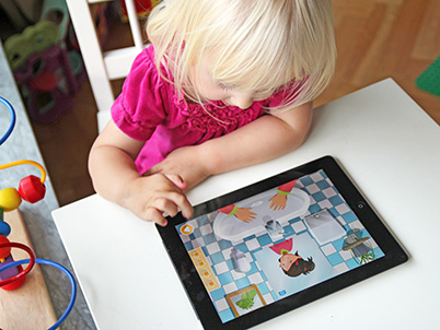 Little girl playing Ella’s handwashing adventure app on a tablet (photo)